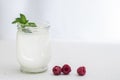 Organic probiotic milk kefir drink or yogurt in glass containers, with raspberry, on the white grey background. Gut health.