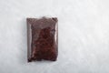 Organic ragi or black quinoa in a transparent package on light grey textured table