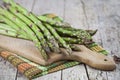 Organic raw garden asparagus on cutting board on rustic wooden table background. Green spring vegetables and cotton napkin Royalty Free Stock Photo