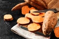 Organic raw sweet potato whole and sliced on wooden kitchen board Royalty Free Stock Photo