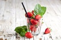 Organic red strawberries glass and mint leaves on rustic wooden background