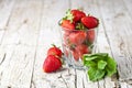 Organic red strawberries glass and mint leaves on rustic wooden background