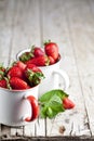 Organic red strawberries in two white ceramic cups and mint leaves on rustic wooden background. Healthy sweet food, vitamins and Royalty Free Stock Photo