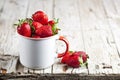 Organic red strawberries in white ceramic cup on rustic wooden background. Healthy sweet food, vitamins and fruity concept Royalty Free Stock Photo