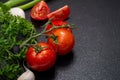 Organic Red Tomatoes on the vine, fresh Curly Parsley, Green Onion Scallions and Garlic arranged on natural black stone Royalty Free Stock Photo