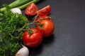 Organic Red Tomatoes on the vine, fresh Curly Parsley, Green Onion Scallions and Garlic arranged on natural black stone Royalty Free Stock Photo