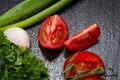 Organic Red Tomatoes on the vine, fresh Curly Parsley, Green Onion Scallions and Garlic arranged on natural black stone Royalty Free Stock Photo