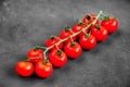 Organic ripe fresh cherry tomatoes on a long branch on black texture background. Healthy vegan food. Royalty Free Stock Photo