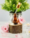 Organic rose serum on wooden podium, rose petals and candles