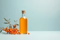 Organic sea buckthorn oil in the bottle with fresh ripe sea buckthorn berries and leaves on pastel background. Natural cosmetic