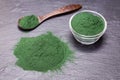 Organic spirulina algae powder on black slate platter background