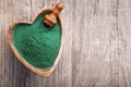 Organic spirulina algae powder in a wooden spoon on wood background