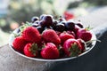 Organic sweet cherry and strawberry on a white plate.