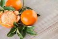 Organic tangerine with green leaves on grey wooden board table