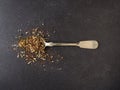 Organic tea blend on a rustic spoon, dark stone background