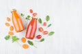 Organic tomato and carrot juices in glass bottles with ingredients and green leaves spinach on white wood board, mock up.