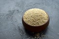 Organic uncooked quinoa grains in wooden bowl on black stone background