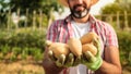 Organic vegetables. Fresh potatoes in the hands of male farmer. Cheerful man Royalty Free Stock Photo