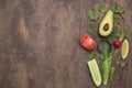 Organic vegetables and herbs on brown abstract background. Copy space, flat lay, top view. Avocado, tomato, green lettuce leaves Royalty Free Stock Photo