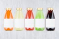 Organic vegetables juices - set of different color juices with cap in glass bottles with blank label on white wood background.