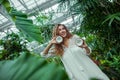Woman in white dress with coconut in her hands in greenhouse