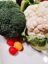 Organically fresh broccoli cauliflower red cherri and yellow tomatoes on a white plate photographed close up,fresh vegetables Royalty Free Stock Photo