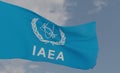 Organization flag International Atomic Energy Agency on the background of clouds, fabric flag IAEA, blue sky background with IAEA