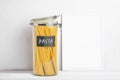 Organization of storage in the kitchen. Pasta in glass container on a kitchen table. White empty frame for text. Zero