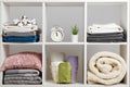 Organization of storage. Stacks of towels, sheets, bed linen, blankets and pillows on a white shelf