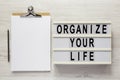 `Organize your life` on a lightbox, clipboard with blank sheet of paper on a white wooden background, top view. Flat lay, overhe Royalty Free Stock Photo