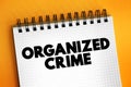 Organized Crime is a continuing criminal enterprise that works to profit from illicit activities, text concept on notepad Royalty Free Stock Photo