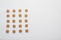 Close-up of an organized arrangement of brown pills on a white background