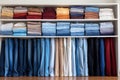 organized stack of jeans and pants on a white shelf