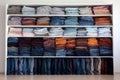 organized stack of jeans and pants on a white shelf