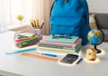 Organized workspace with a blue backpack, stacked notebooks, and a pair of glasses on top. A small Royalty Free Stock Photo