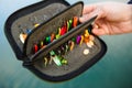 Organizer with a set of artificial lures for fishing in the hands of a fisherman. Royalty Free Stock Photo