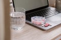 Organizer weekly shots with glass of water on workplace background and laptop Closeup of medical pill box with doses of Royalty Free Stock Photo