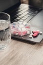 Organizer weekly shots with glass of water on workplace background and laptop Closeup of medical pill box with doses of Royalty Free Stock Photo