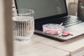 Organizer weekly shots with glass of water on workplace background and laptop Closeup of medical pill box with doses of Royalty Free Stock Photo