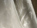 Organza in white and beige or champagne color close-up. Lightweight sheer tulle curtains under side lighting