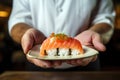 Oriental chef\'s hands holding traditional sushi with red fish