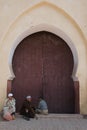 Oriental door. Old moroccan men sitting in front of red painted wooden door with oriental frame. Royalty Free Stock Photo