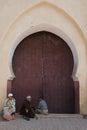 Oriental door. Old moroccan men sitting in front of red painted wooden door with oriental frame. 