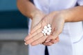 Oriental female hands of a social worker in a medical gown holding a handful of white pills in the palms on the street