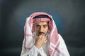 Oriental man in white, traditional, national, Arabic dress dishdash, thoughtfully looking holding his hand at his chin