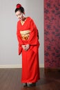 Oriental model in red Japanese kimono bowing