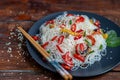 Oriental rice noodles Udon with sweet pepper, mushrooms. On a wooden background
