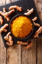 Oriental spice turmeric powder in a bowl and fresh root close-up. Vertical top view Royalty Free Stock Photo