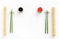 Oriental table set up. Chopsticks, ginger, soy sause, bamboo mat on white background top-down frame copy space