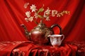 an oriental teapot with traditional asian motifs, set against a red silk backdrop